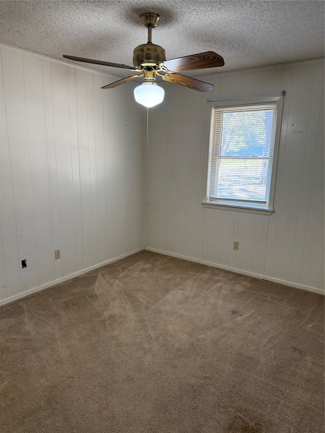 carpeted spare room featuring wood walls, ceiling fan, and a textured ceiling