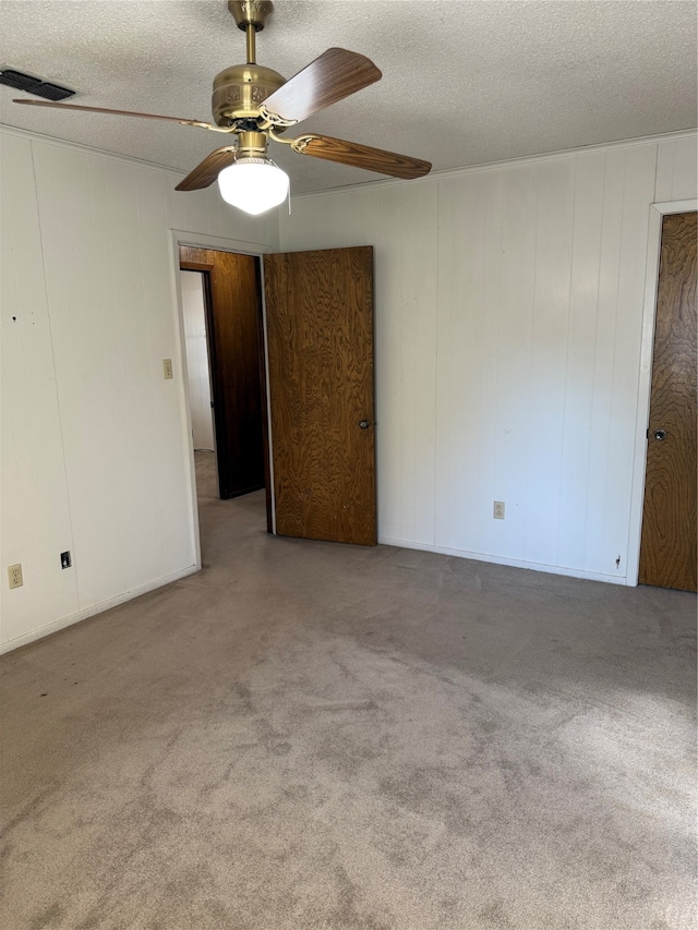 carpeted empty room with ceiling fan and a textured ceiling