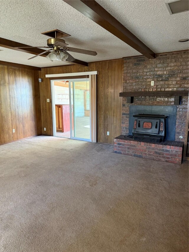 unfurnished living room featuring wooden walls, beam ceiling, a textured ceiling, and dark carpet