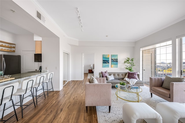 living room with dark hardwood / wood-style flooring, track lighting, and ornamental molding