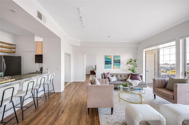 living room featuring hardwood / wood-style flooring, rail lighting, and ornamental molding