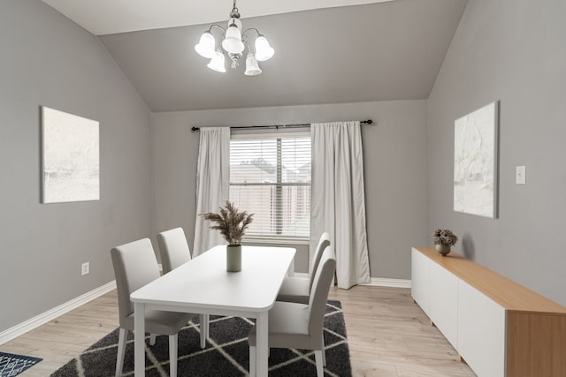 dining space featuring a notable chandelier, light hardwood / wood-style floors, and vaulted ceiling