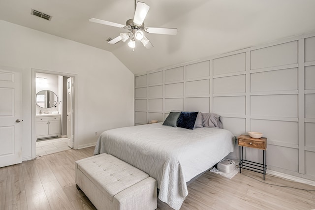 bedroom featuring ceiling fan, ensuite bath, light wood-type flooring, and lofted ceiling