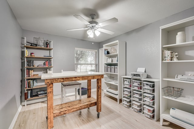 home office with light hardwood / wood-style floors and ceiling fan