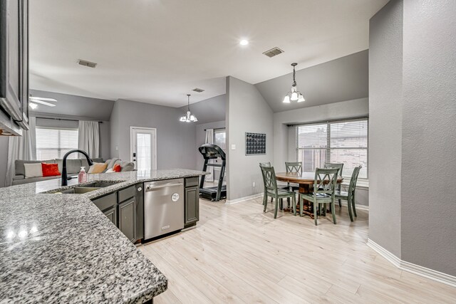 kitchen with sink, stainless steel dishwasher, light stone counters, and vaulted ceiling