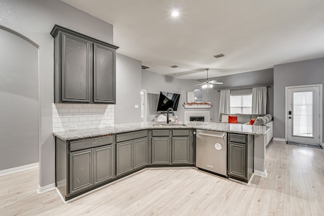 kitchen with light stone countertops, tasteful backsplash, dishwasher, and kitchen peninsula