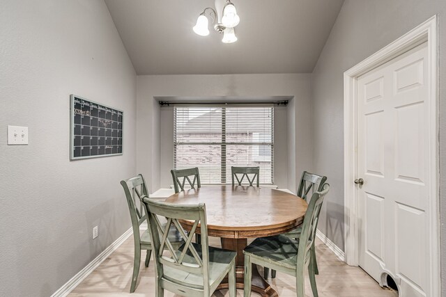 dining space featuring light wood-type flooring, vaulted ceiling, and a notable chandelier