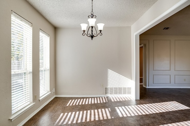 empty room featuring a textured ceiling and a notable chandelier