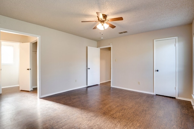 empty room featuring a textured ceiling, ceiling fan, and dark wood-type flooring