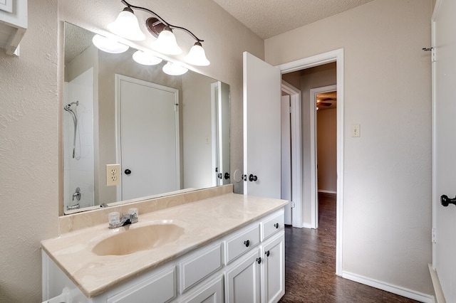 bathroom with vanity, a shower, a textured ceiling, and hardwood / wood-style flooring