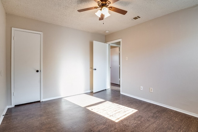 unfurnished bedroom with a textured ceiling, dark hardwood / wood-style floors, and ceiling fan