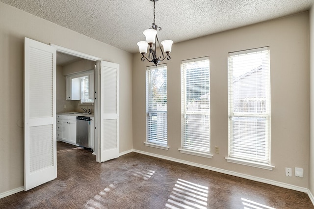 unfurnished dining area featuring dark hardwood / wood-style flooring, a textured ceiling, a wealth of natural light, and a chandelier