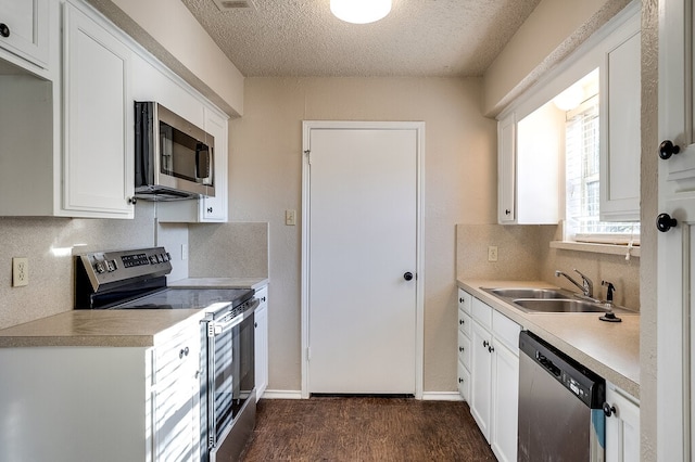 kitchen featuring sink, dark wood-type flooring, a textured ceiling, white cabinets, and appliances with stainless steel finishes