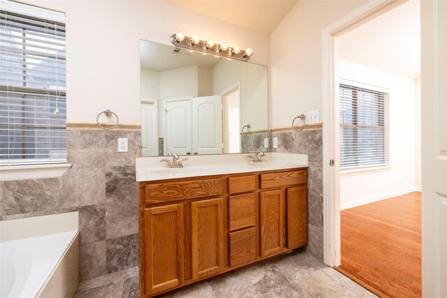 bathroom with a tub, vanity, tile walls, and hardwood / wood-style flooring