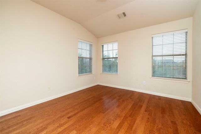 spare room featuring hardwood / wood-style floors and lofted ceiling