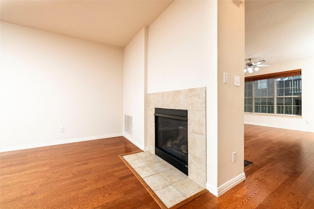 unfurnished living room with ceiling fan, light wood-type flooring, and a tile fireplace