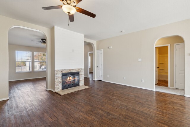 unfurnished living room with ceiling fan, a fireplace, and dark hardwood / wood-style flooring