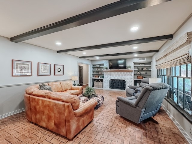 living room with beamed ceiling, built in shelves, and a fireplace