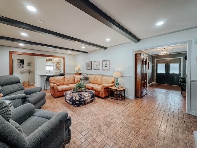 living room with a chandelier, beam ceiling, a wealth of natural light, and french doors