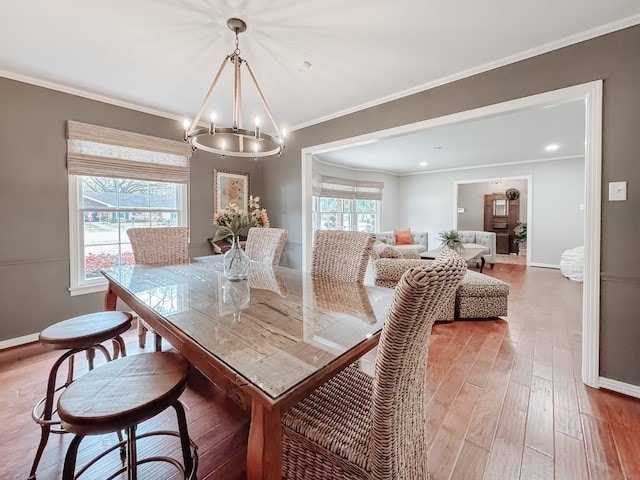 dining area featuring a chandelier, wood-type flooring, plenty of natural light, and ornamental molding