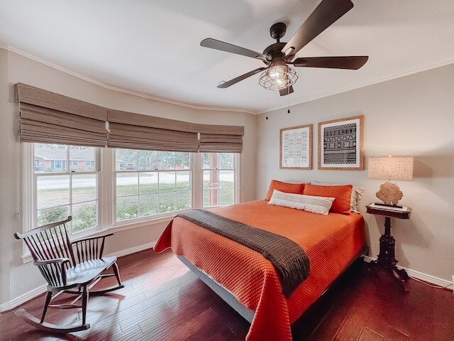 bedroom with ceiling fan, ornamental molding, and dark wood-type flooring