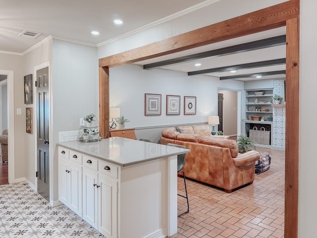 kitchen featuring white cabinets, a kitchen breakfast bar, built in features, and ornamental molding