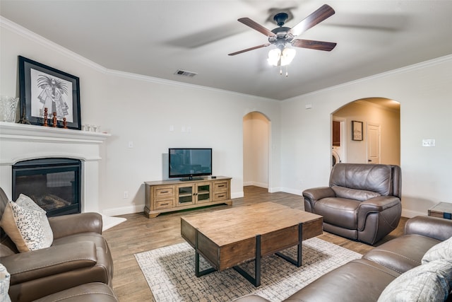 living room featuring light hardwood / wood-style floors, ceiling fan, and ornamental molding