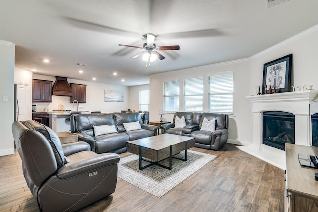 living room featuring crown molding, ceiling fan, and light wood-type flooring