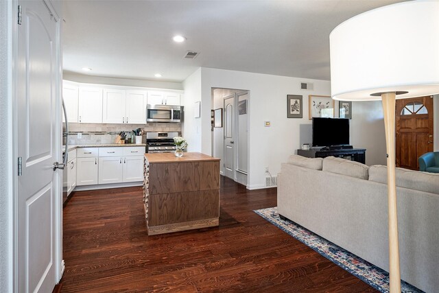 kitchen with appliances with stainless steel finishes, dark hardwood / wood-style floors, butcher block countertops, white cabinetry, and decorative backsplash