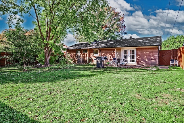 rear view of house with french doors and a lawn