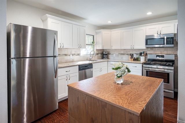 kitchen with sink, white cabinetry, stainless steel appliances, a kitchen island, and decorative backsplash