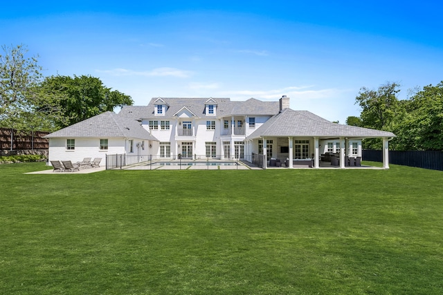 rear view of house featuring a yard, a fenced in pool, and a patio area