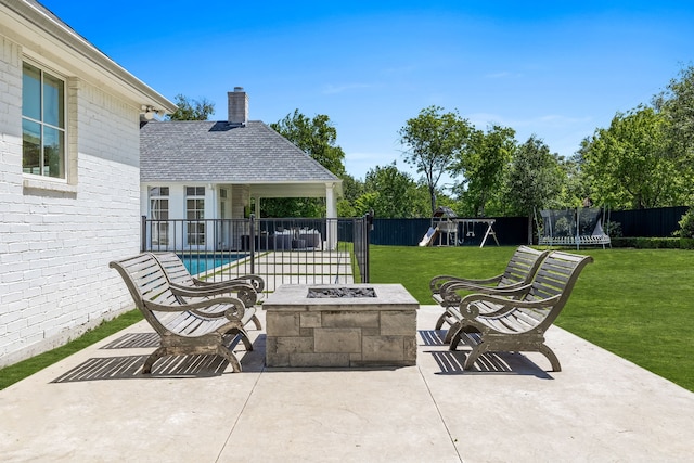 view of patio with a playground, a fire pit, an outbuilding, a trampoline, and a fenced in pool