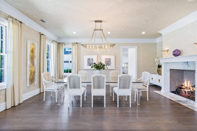 dining area with dark hardwood / wood-style flooring, a notable chandelier, crown molding, and a high end fireplace