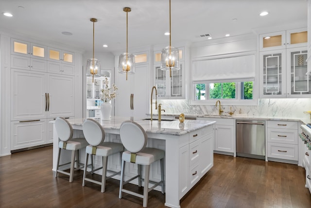 kitchen with hanging light fixtures, light stone countertops, white cabinets, a center island with sink, and stainless steel dishwasher