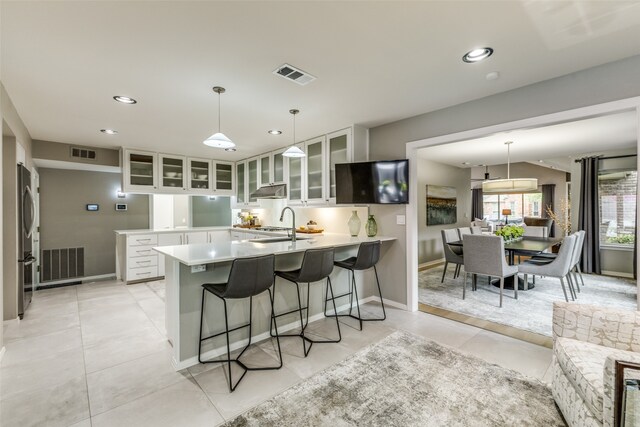 kitchen featuring stainless steel refrigerator, kitchen peninsula, white cabinets, and hanging light fixtures