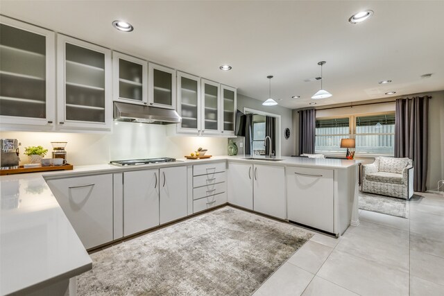 kitchen featuring sink, hanging light fixtures, stainless steel gas cooktop, kitchen peninsula, and white cabinets