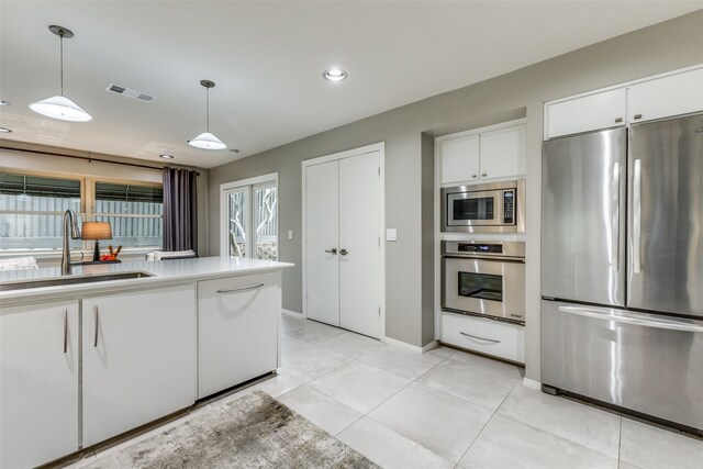 kitchen with white cabinetry, sink, stainless steel appliances, pendant lighting, and light tile patterned floors