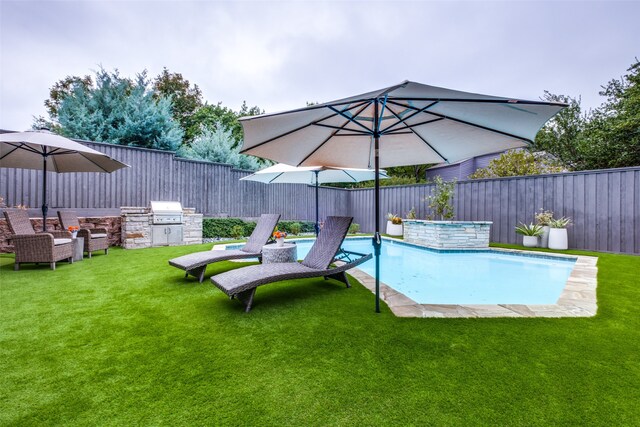 view of pool featuring a yard, a grill, and exterior kitchen