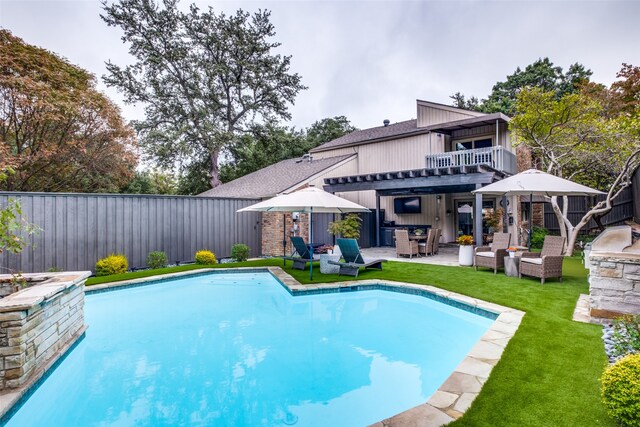 view of pool with a patio, outdoor lounge area, exterior kitchen, a yard, and an outdoor bar