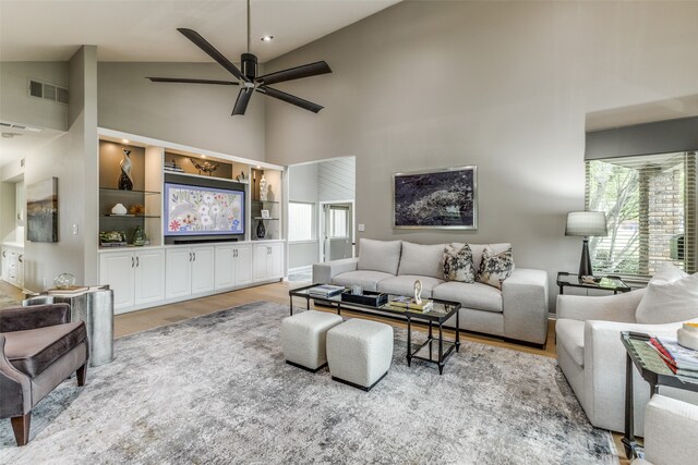 living room with plenty of natural light, ceiling fan, light wood-type flooring, and high vaulted ceiling