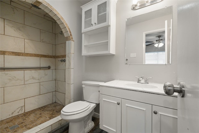 bathroom featuring ceiling fan, toilet, vanity, and tiled shower