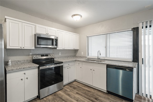 kitchen with sink, light stone counters, dark hardwood / wood-style flooring, white cabinets, and appliances with stainless steel finishes