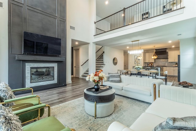 living room featuring wood-type flooring, a towering ceiling, and a fireplace