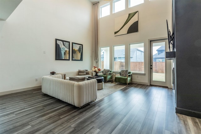 living room featuring a towering ceiling and dark wood-type flooring