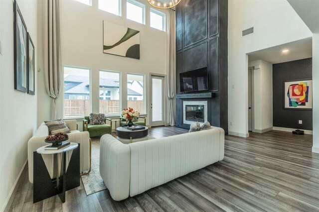 living room with a high ceiling, a large fireplace, and hardwood / wood-style flooring