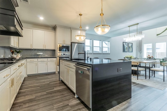 kitchen featuring decorative backsplash, white cabinetry, hanging light fixtures, and appliances with stainless steel finishes