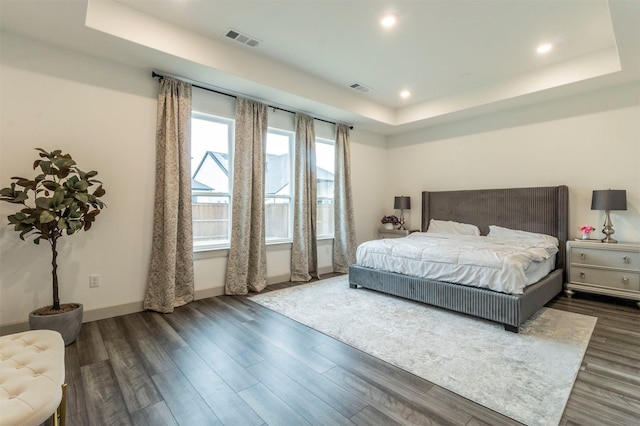 bedroom with a tray ceiling and dark hardwood / wood-style flooring