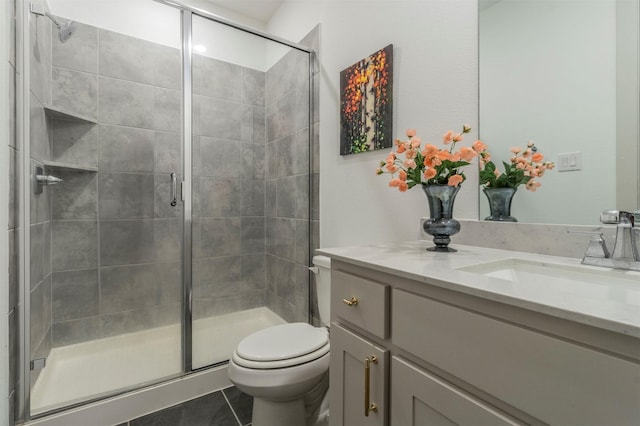 bathroom featuring tile patterned flooring, vanity, toilet, and a shower with door