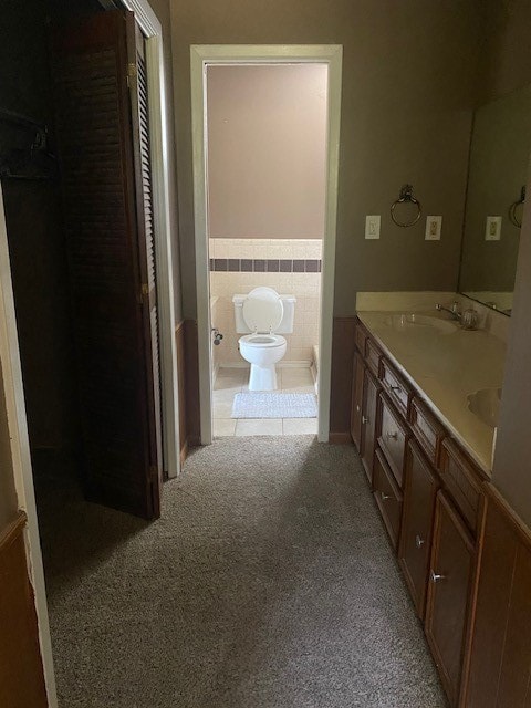 bathroom featuring vanity, toilet, and tile walls